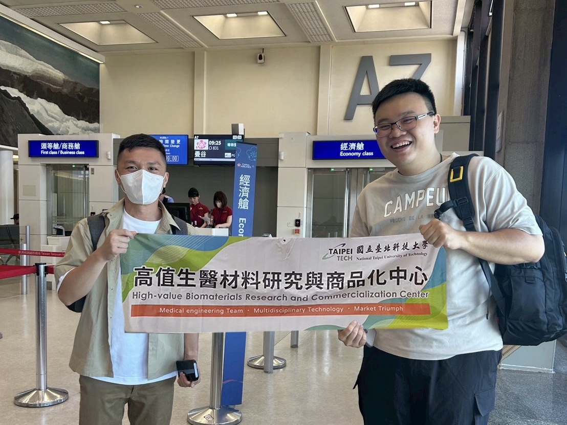 Dr. Yu-Cheng Chang and Dr. Shih-Hao Huang pose for a photo at the airport while holding the Center’s banner
