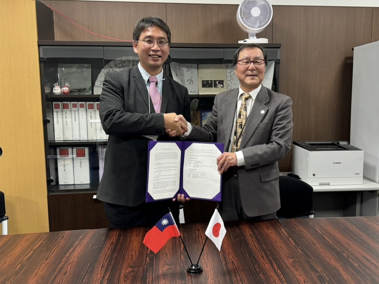 北科大研發長莊賀橋教授與筑波大學副校長金保安則握手,並且拿著合作備忘錄(MOU)合影留念。