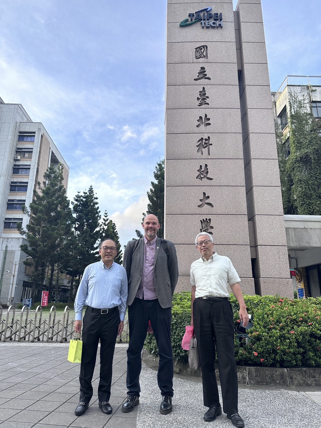 方旭偉教授、笠井均教授以及 Liam Grover 教授在北科大校門口合照留影。