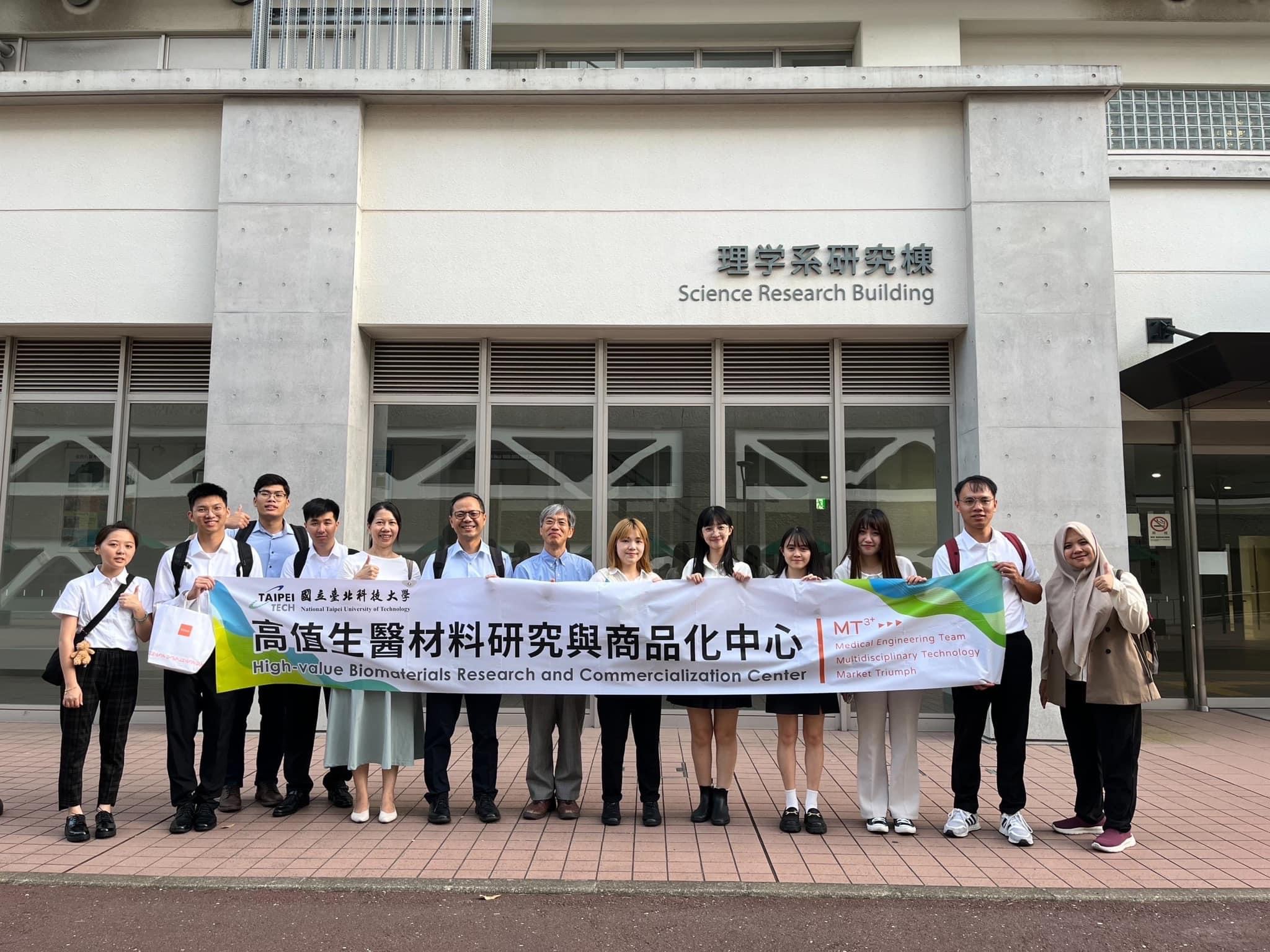 Center members and students participating in the exchange pose for a group photo while holding the center banner.