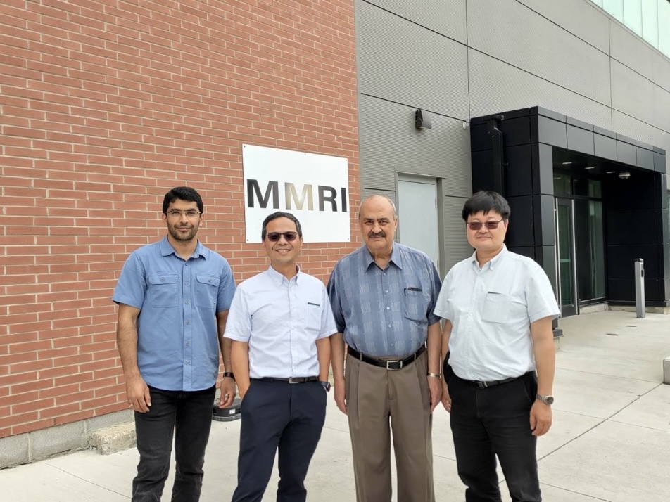 Professor Cho-Pei Jiang posing for a group photo with the Director of the Additive Manufacturing Centre and other professors at the entrance of the Additive Manufacturing Centre at McMaster University.