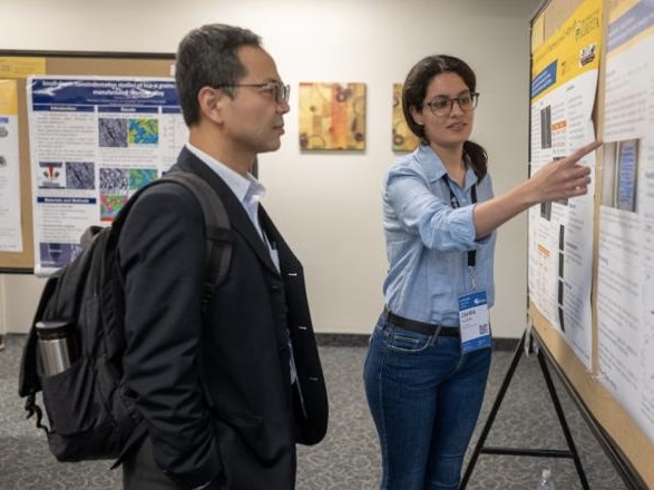 Professor Cho-Pei Jiang listening to a student presenting their research poster.