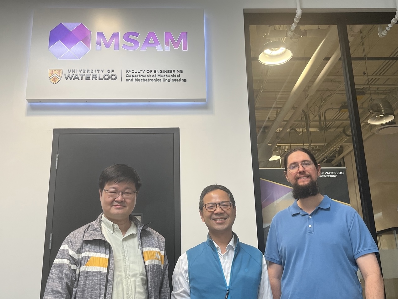 Professors posing for a group photo in front of the Multi-Scale Additive Manufacturing Laboratory at the University of Waterloo.