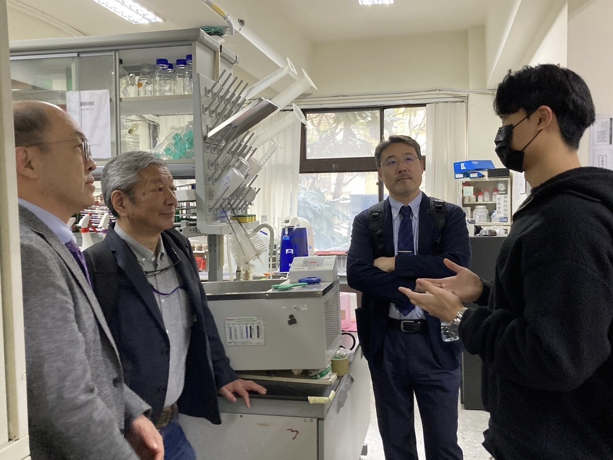 A laboratory student presents their research to Professor Akira Matsumoto and other faculty members.
