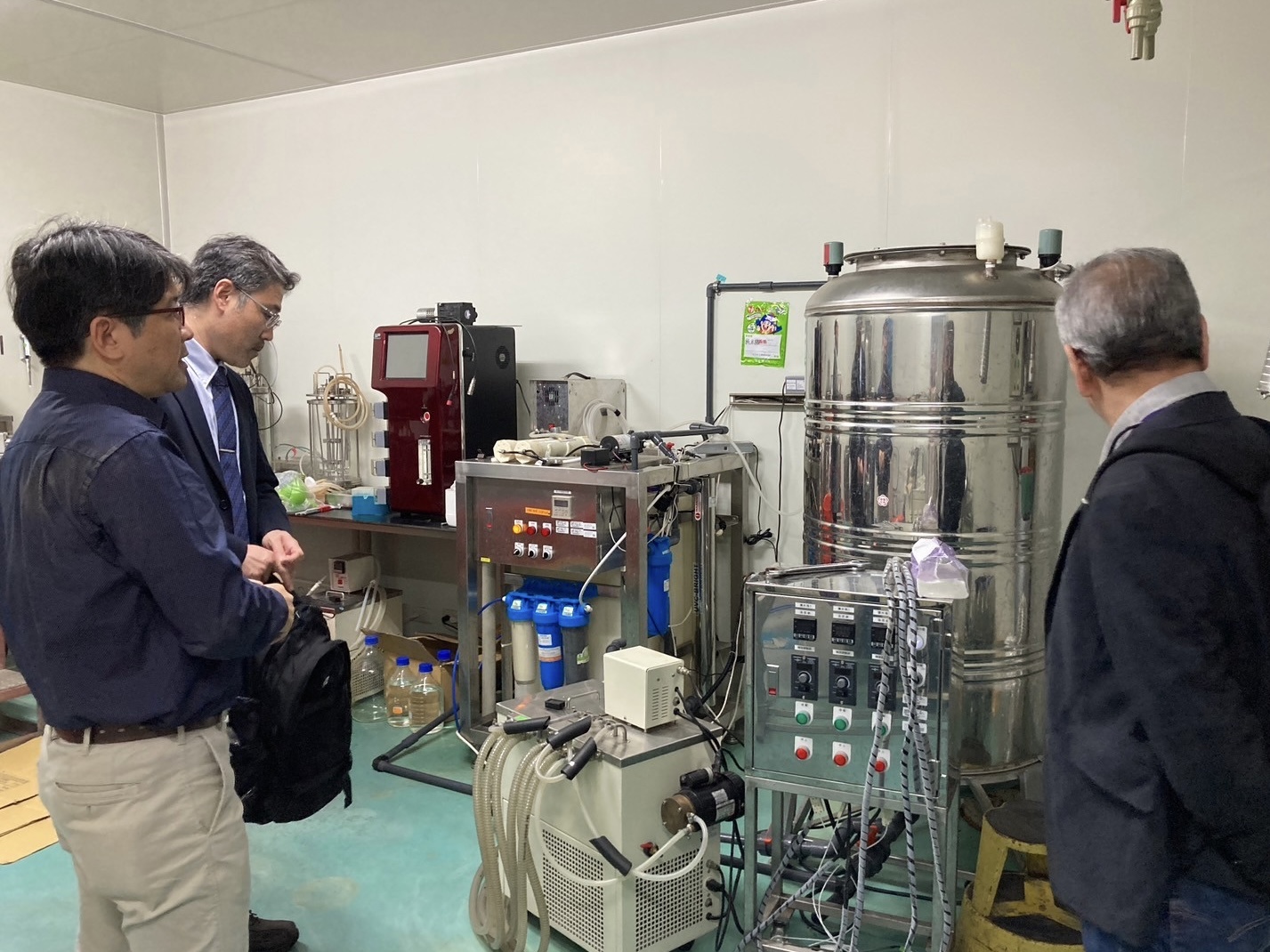 The professors are exchanging experience in operating laboratory equipment.