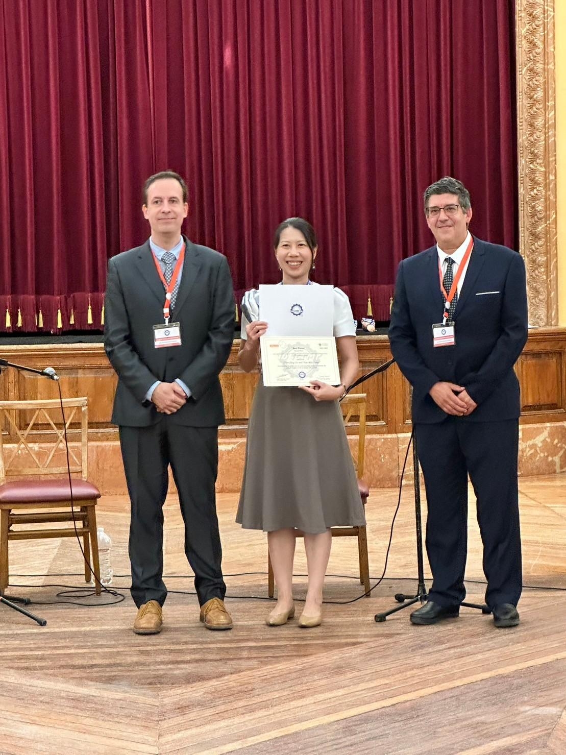 Assistant Research Professor Chen-Ying Su poses for a photo while receiving an award on stage.