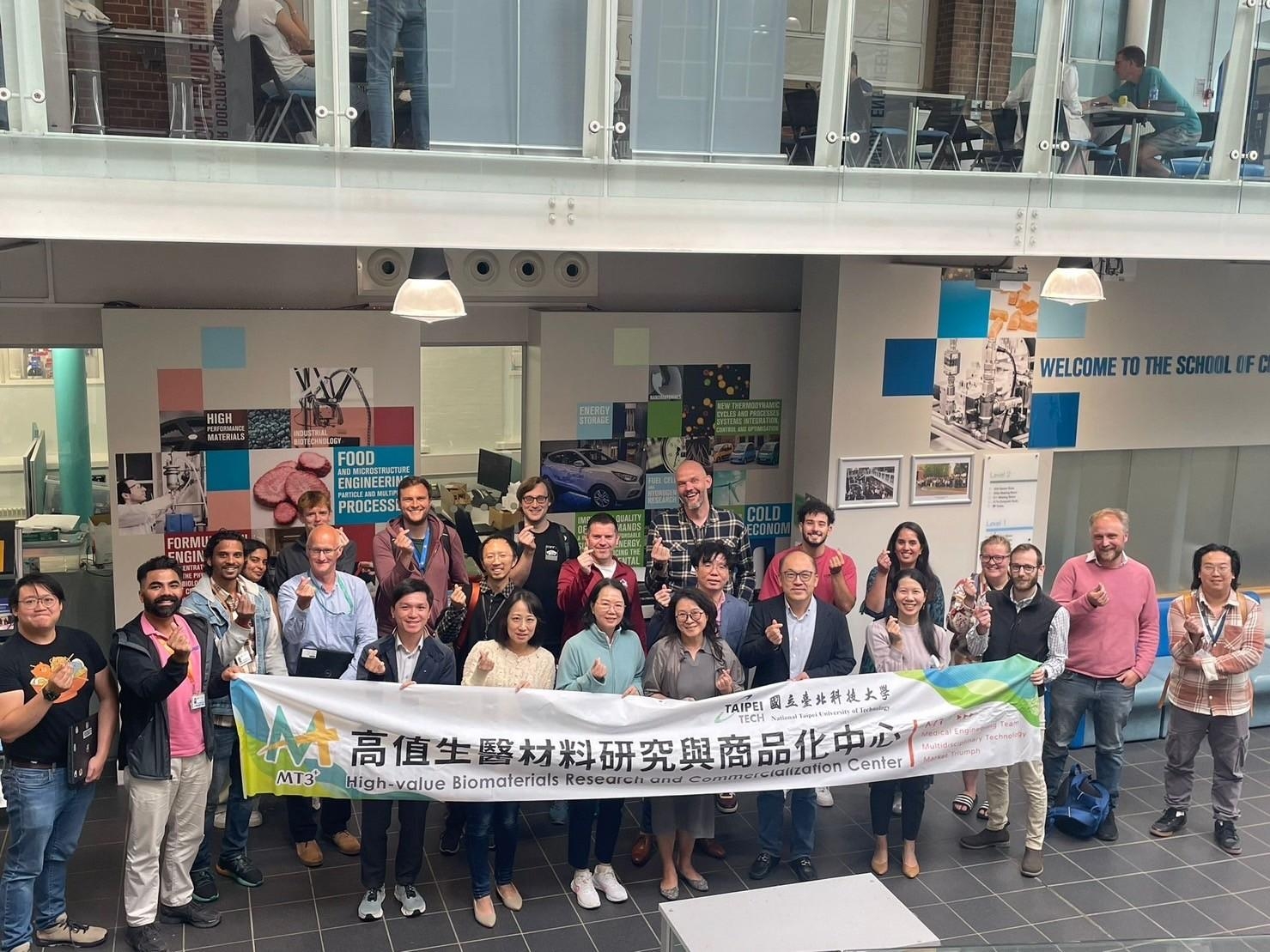 Group photo of the visiting delegation and the benchmark center staff holding a banner.