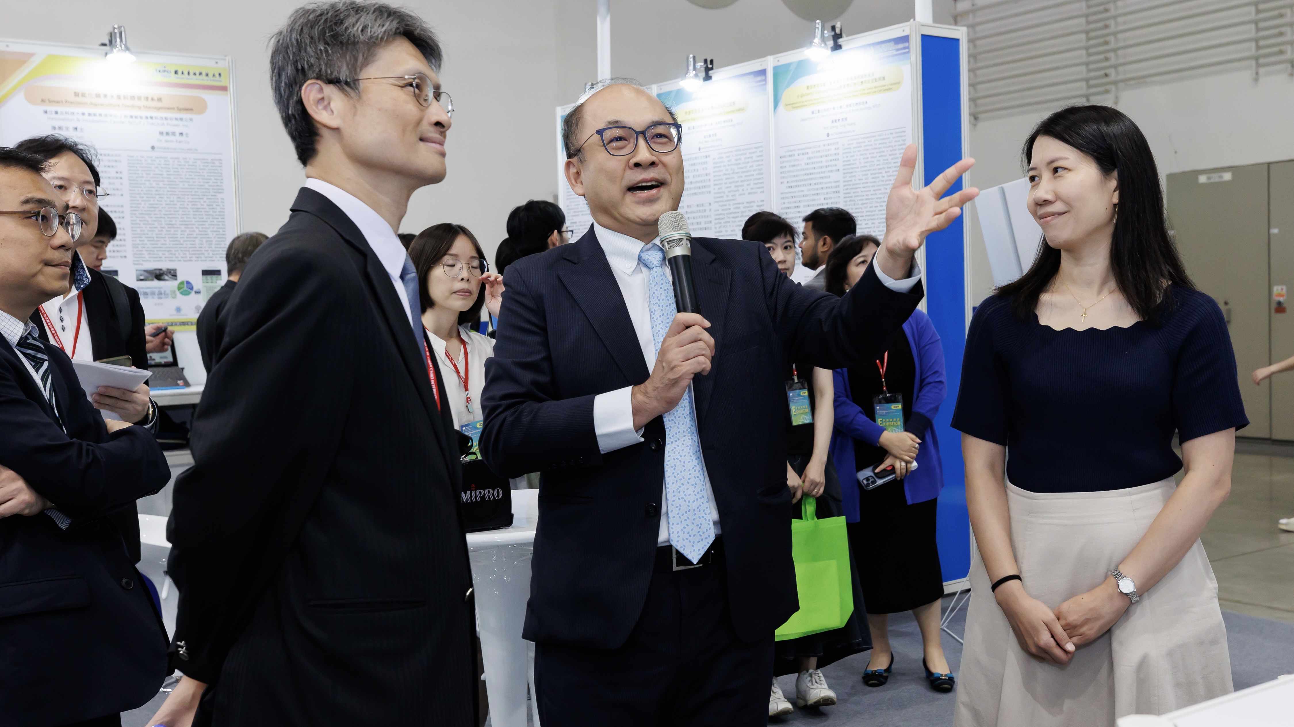 Professor Hsu-Wei Fang introduces the exhibits at the booth to the distinguished guests.