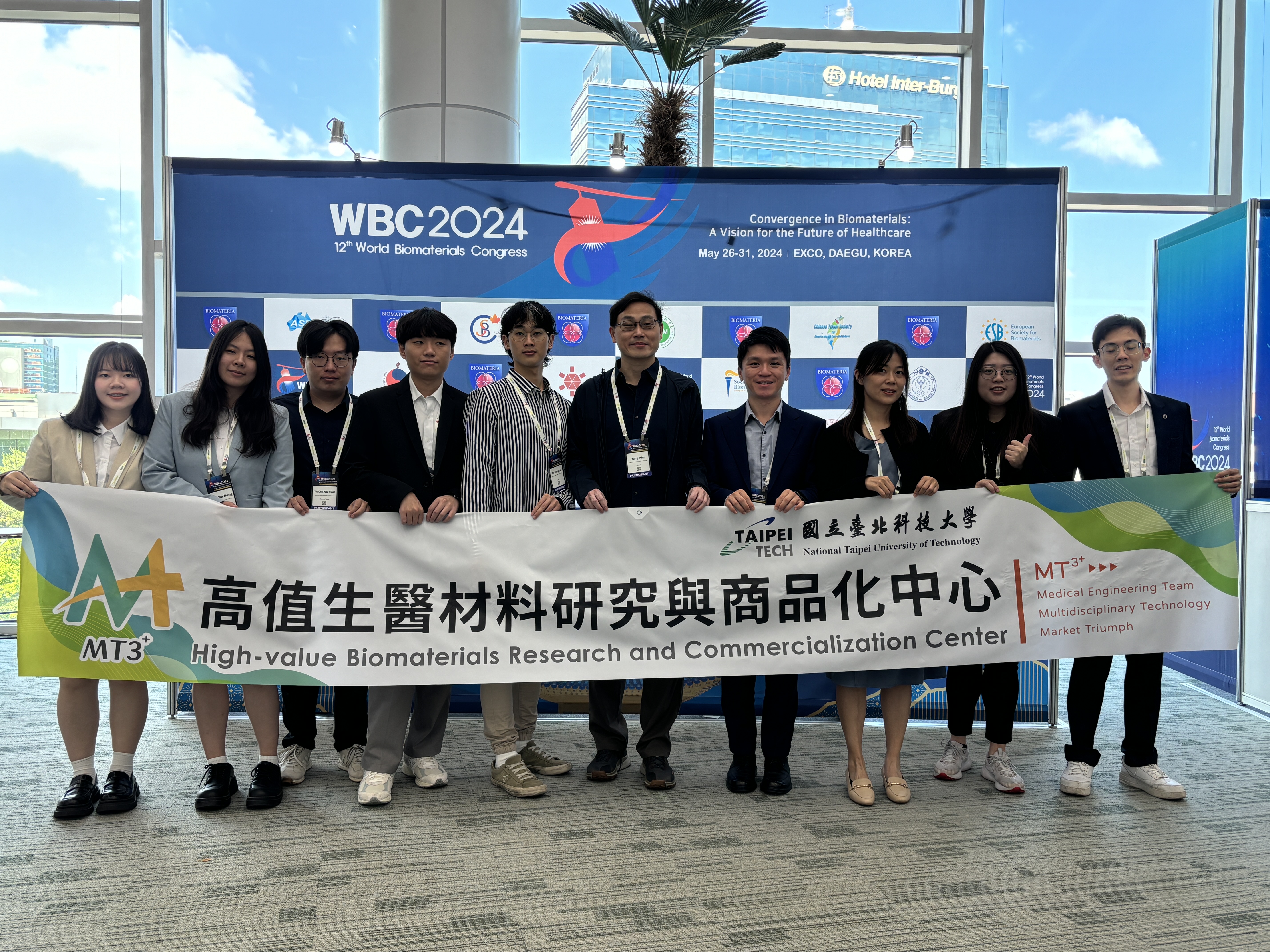 Group photo of all participants holding the Center’s banner in front of the event photo wall