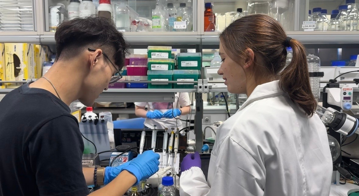 A student is instructing Dr. Justina Karčiauskaitė on how to use the laboratory equipment