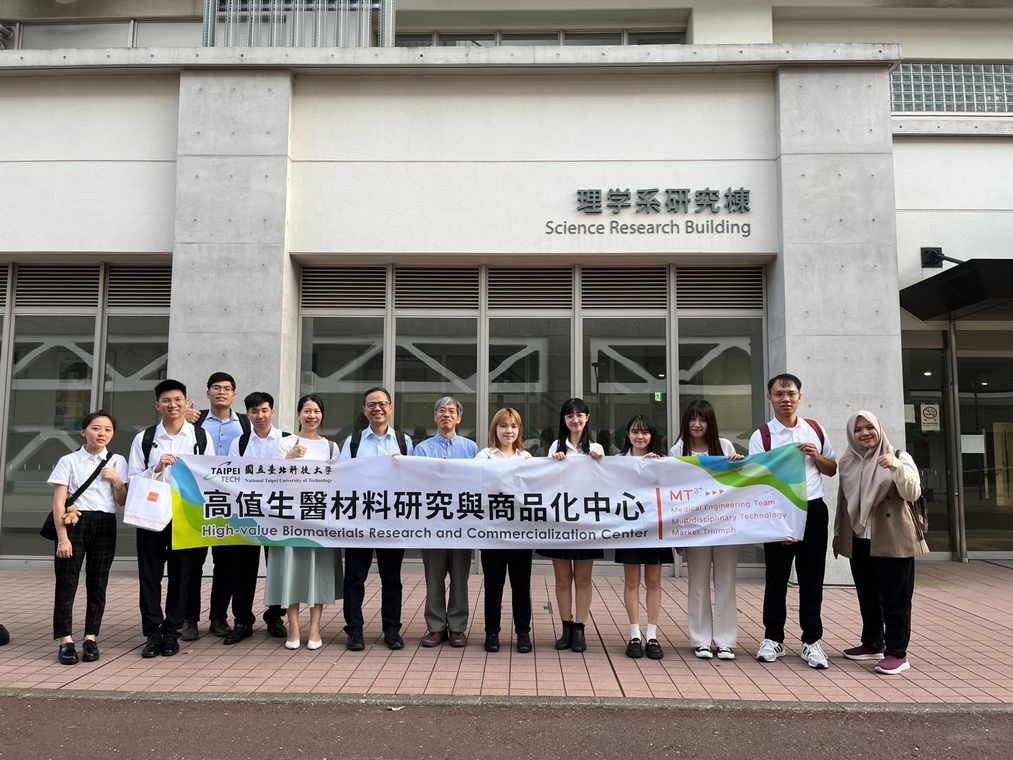 The professor and students pose for a group photo with a banner outside the conference venue